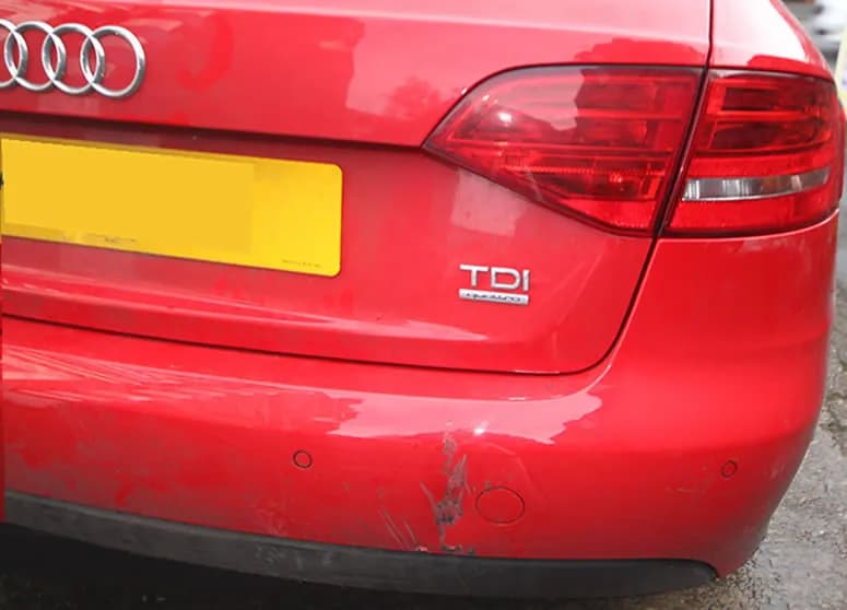 A red Audi with a damaged front bumper before repair.