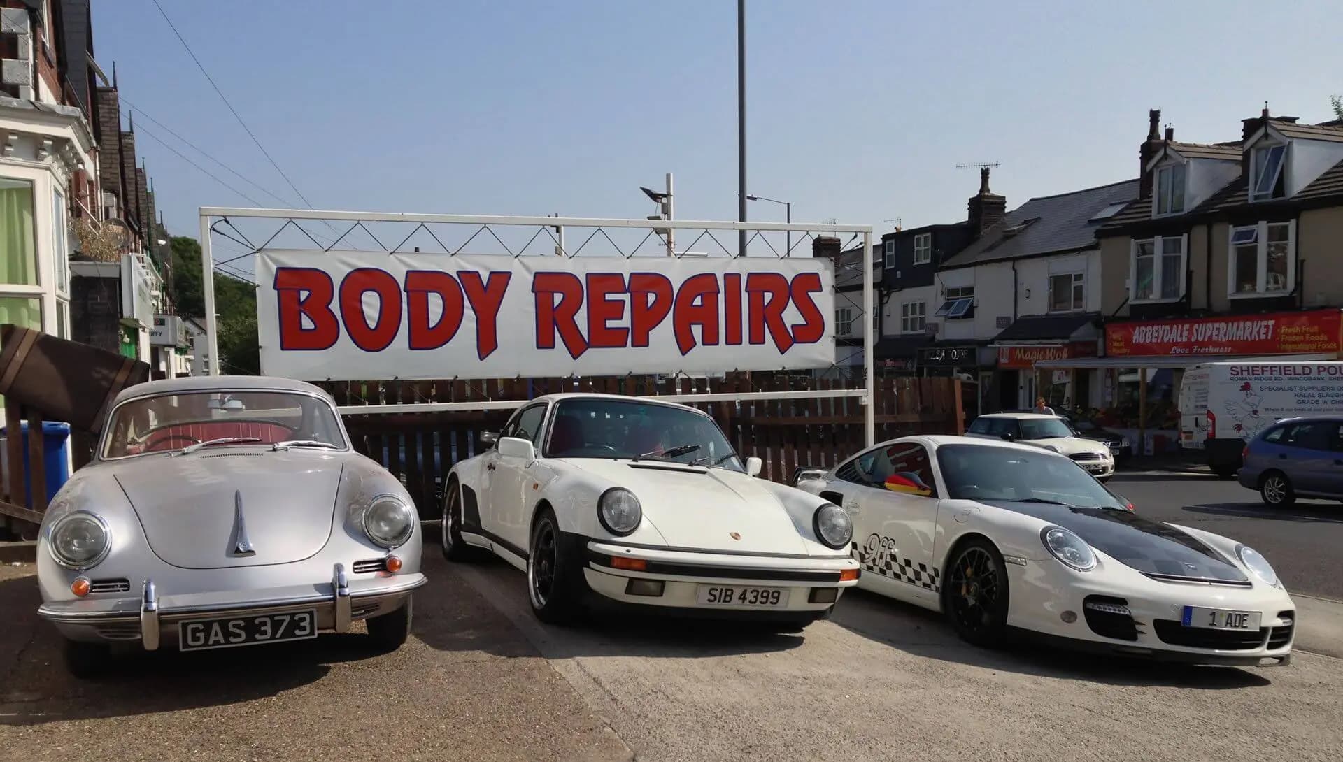 Three classic Porsches lined up under the John Bee Body Repairs sign on Abbeydale Road.