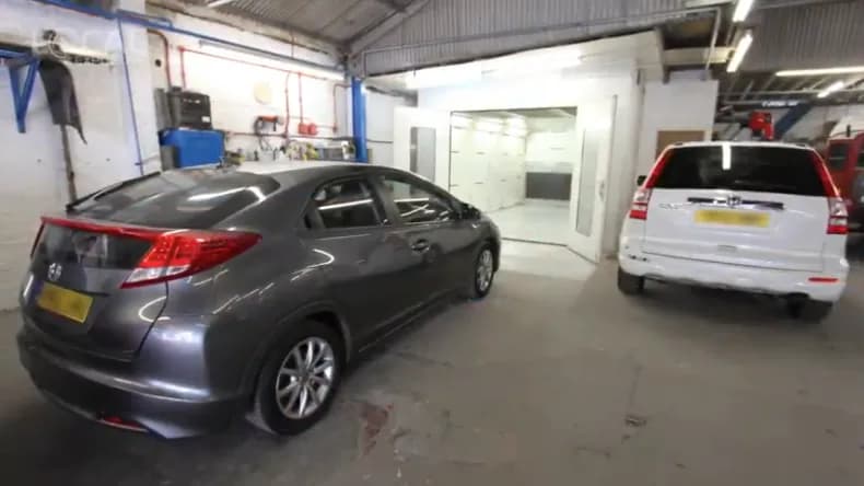 Inside the John Bee workshop with cars in the spray booth bay.